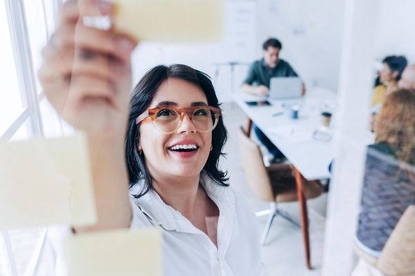 Woman in a meeting explains the advantages of LANCOM Cloud Self Service for network management to her colleagues.