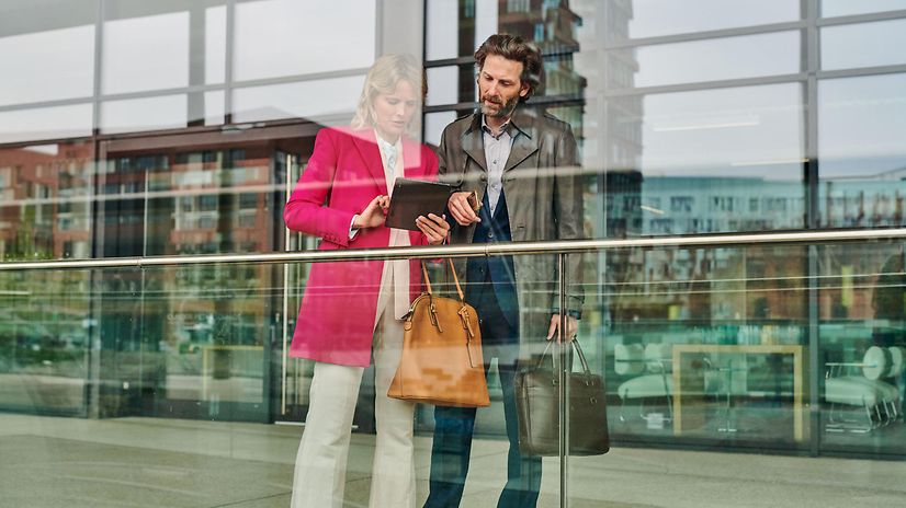 Man and woman looking at tablet in front of office building