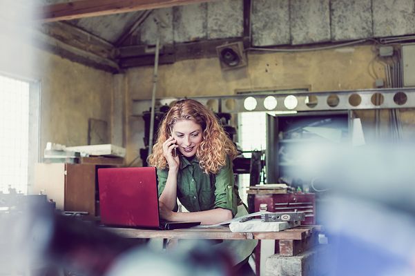 Woman sitting at her desk, surfing the internet and making phone calls with the help of the FRITZ!Box 5690 Pro