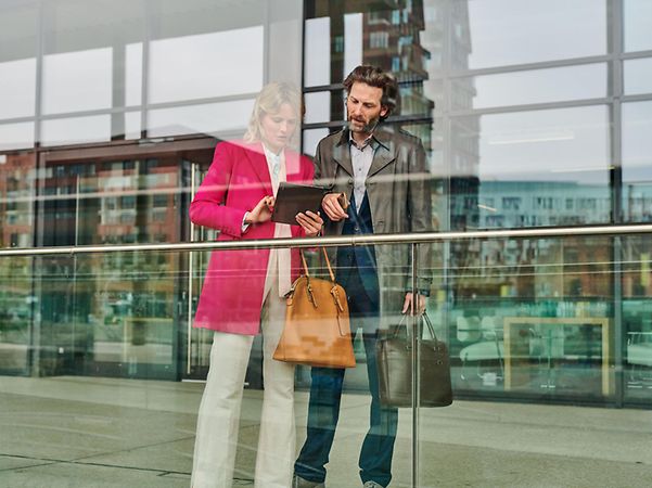 Man and woman looking at tablet in front of office building