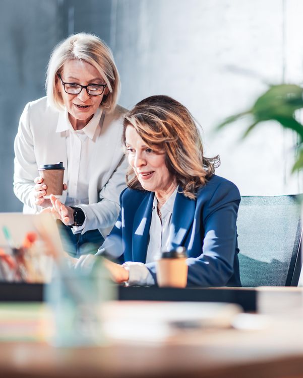 Two women use Webshop's intuitive drag-and-drop editor to add images and videos to their online shop on their laptop.