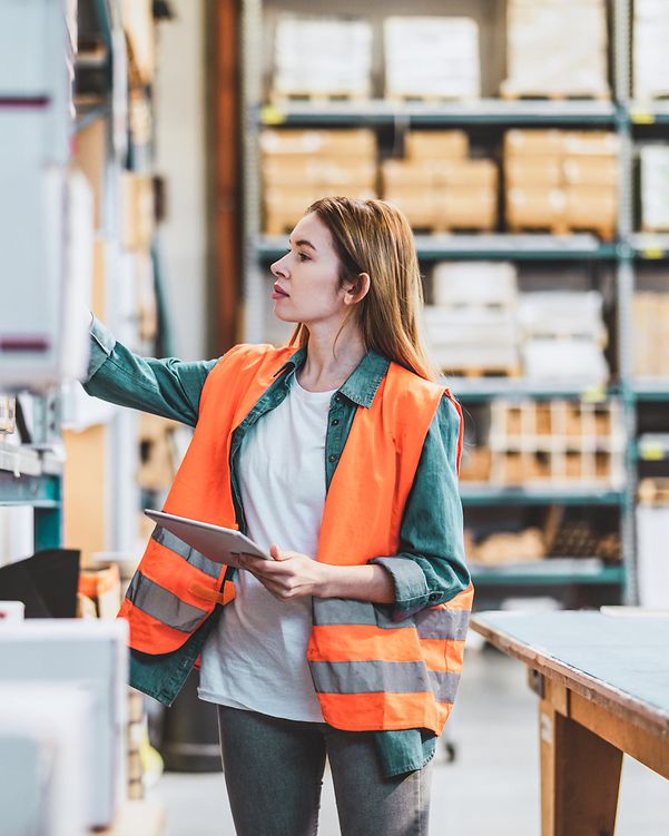 A woman searches for a parcel on a shelf to fulfil an online order from her web shop.