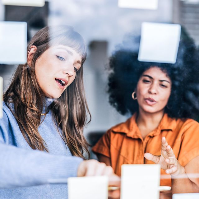 Two women are discussing suitable domain names for their company's website with the help of Post-it notes.