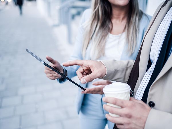 A man shows a woman Telekom's domain name service on a tablet.