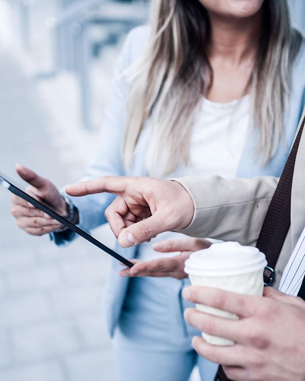 A man shows a woman Telekom's domain name service on a tablet.