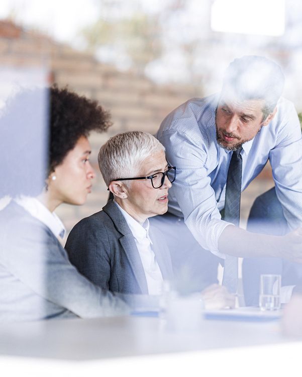 Mehrere Mitarbeitende beraten sich im Büro, dank Telekom IT-Support mit maximalem Datenschutz und IT-Sicherheit.