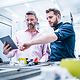 Two men are looking at a tablet.