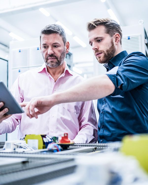 Two men are looking at a tablet.
