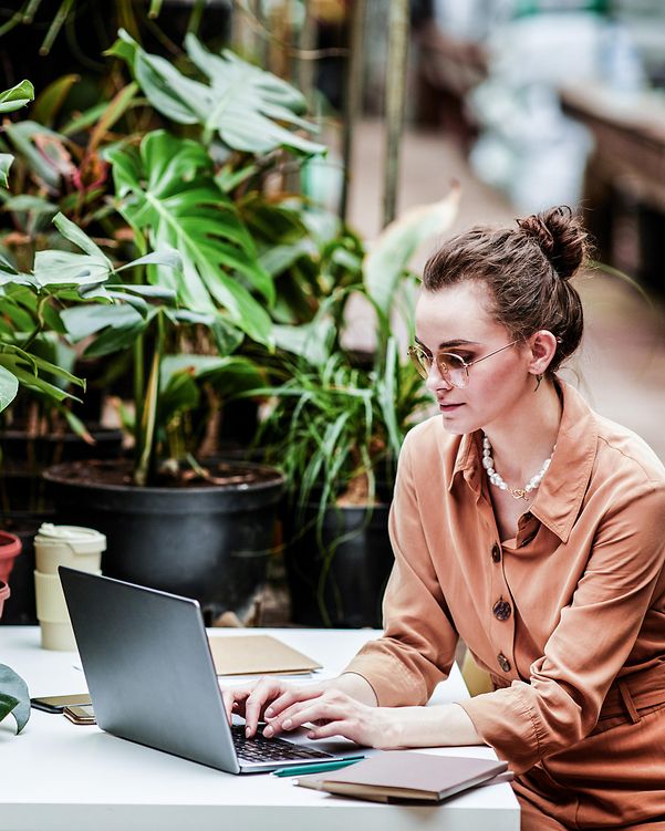 Woman working remotely in green surroundings – modern working with a focus on T Business sustainability