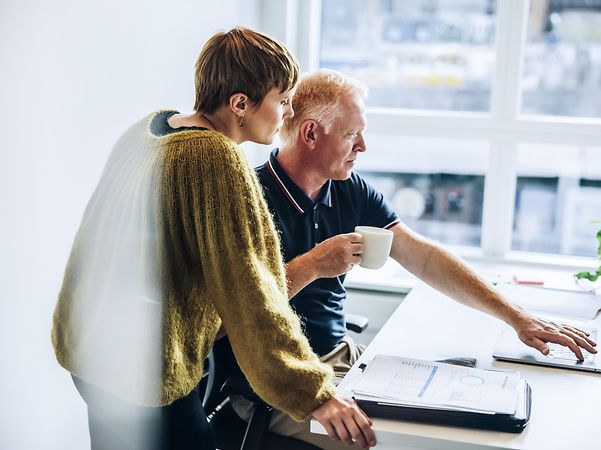Ein Mann zeigt einer Frau den Telekom Ratgeber Festnetz und Internet am Laptop.