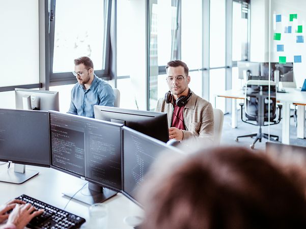Two men are sitting and looking at their screens.