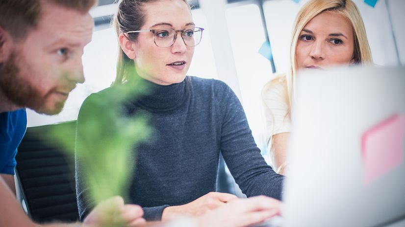 Three people are looking intently at a screen.