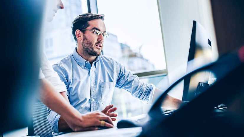 Man looking at a screen, with a telephone in the foreground.