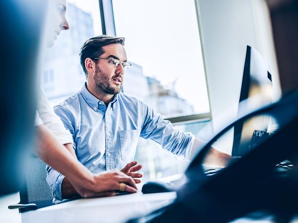 Man looking at a screen, with a telephone in the foreground.