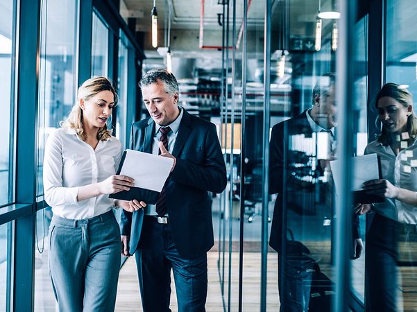 A man is talking to a woman who has notes in her hand.