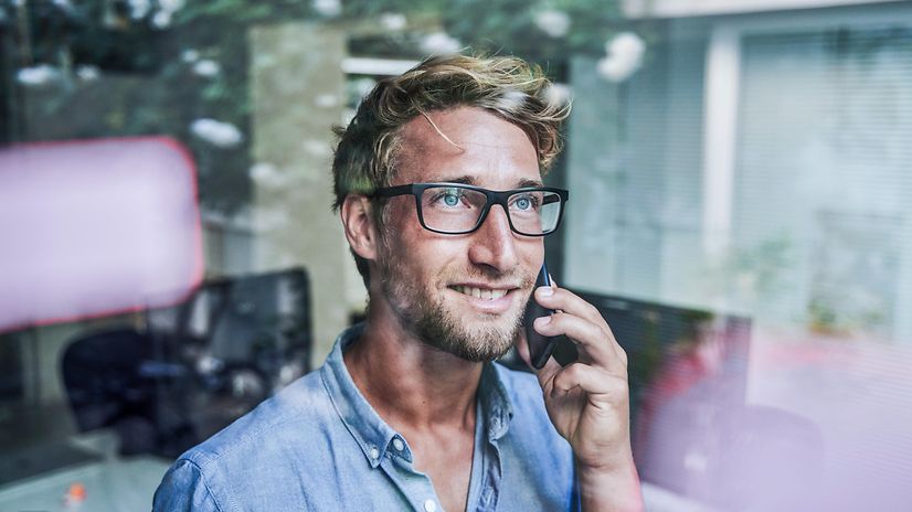 A man is on the phone and looking out of the window.