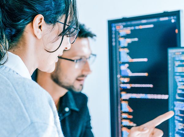 A woman and a man are looking at a screen.