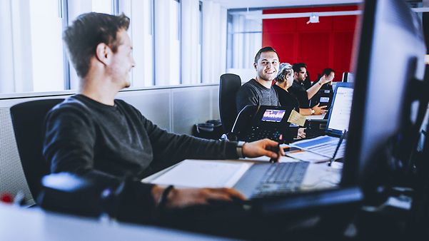 Several people are sitting next to each other and looking at their screens.