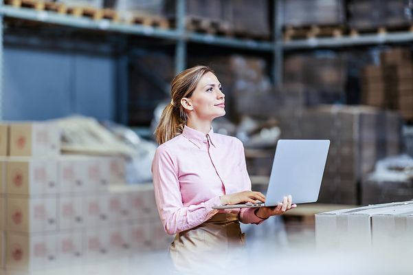Woman standing in a warehouse with a laptop