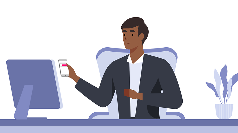 Man at desk with smartphone in hand looking at monitor