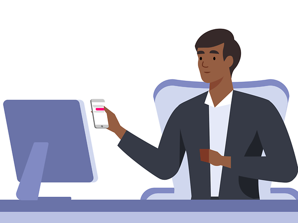 Man at desk with smartphone in hand looking at monitor