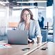 Smiling businesswoman with glasses working on a laptop in a modern office in a company