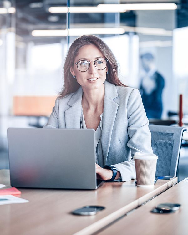 Smiling businesswoman with glasses working on a laptop in a modern office in a company
