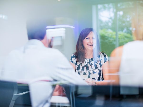 Three colleagues are sitting together at a table and chatting.