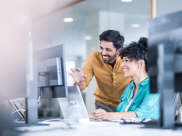 A woman and a man look together at a screen showing Telekom solutions for mobile communication with customers.