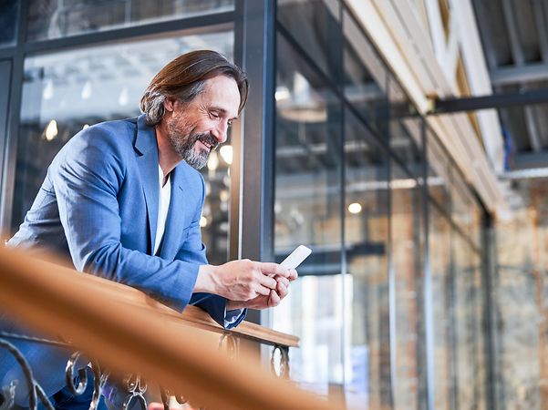 A smiling businessman is delighted with his company's dedicated internet access as he looks at his mobile phone.