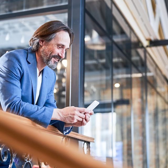 A smiling businessman is delighted with his company's dedicated internet access as he looks at his mobile phone.