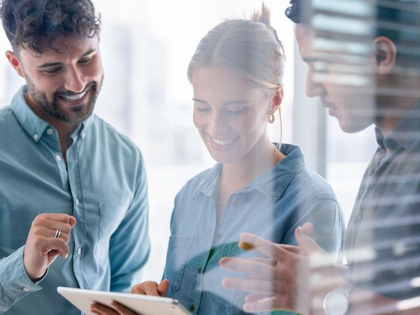 Three people are looking at a tablet together.