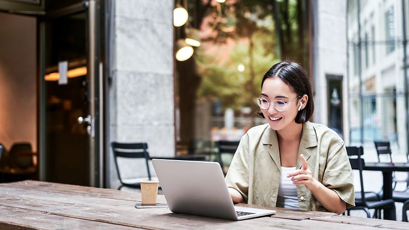 A woman is sitting in front of her laptop and talking on the phone.
