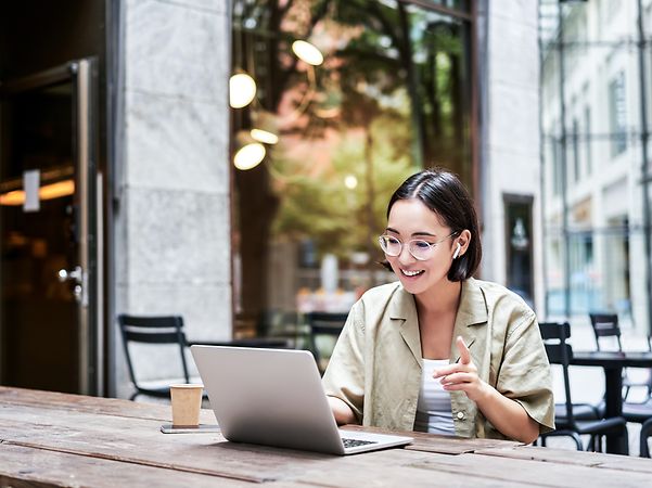 A woman is sitting in front of her laptop and talking on the phone.