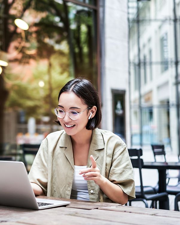 A woman is sitting in front of her laptop and talking on the phone.