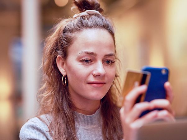 A woman is holding her smartphone and a credit card in her hands.
