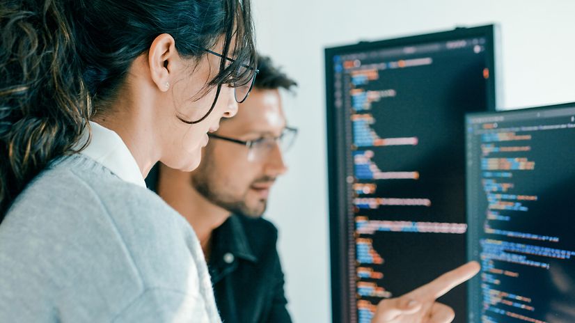 Two colleagues confer in front of a screen displaying data on Telekom's network solutions.