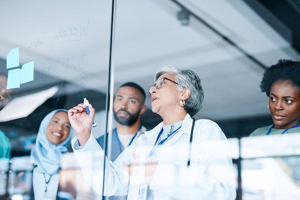 Several doctors stand in front of a planning board in a hospital and use the telematics solution.