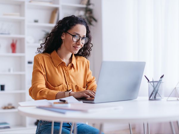 A woman is sitting at her computer, looking up information about Magenta Secure SASE Ecoplay Cisco