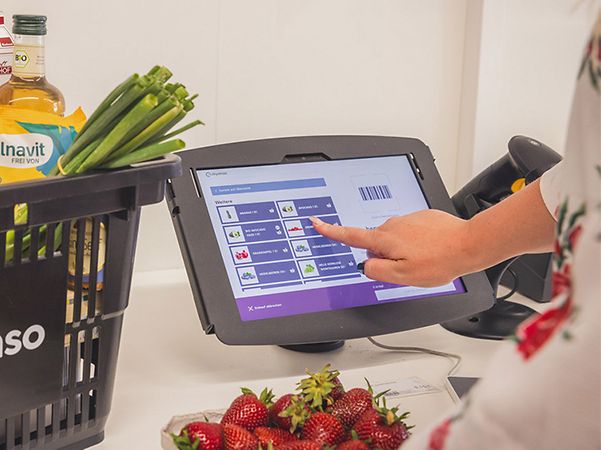 Grey shopping basket from tanteenso with goods next to the self-checkout till