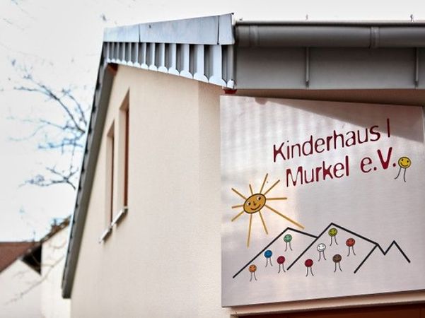 Bright exterior wall of Children's House 1 with colourful Murkel e.V. logo.