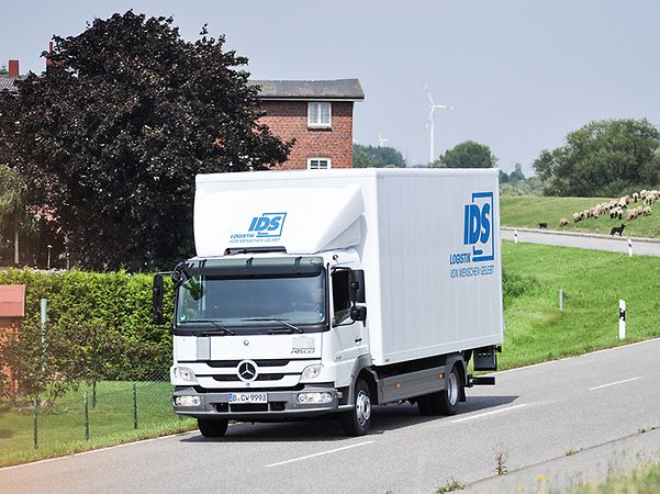 White lorry from IDS Logistik on a country road in rural surroundings