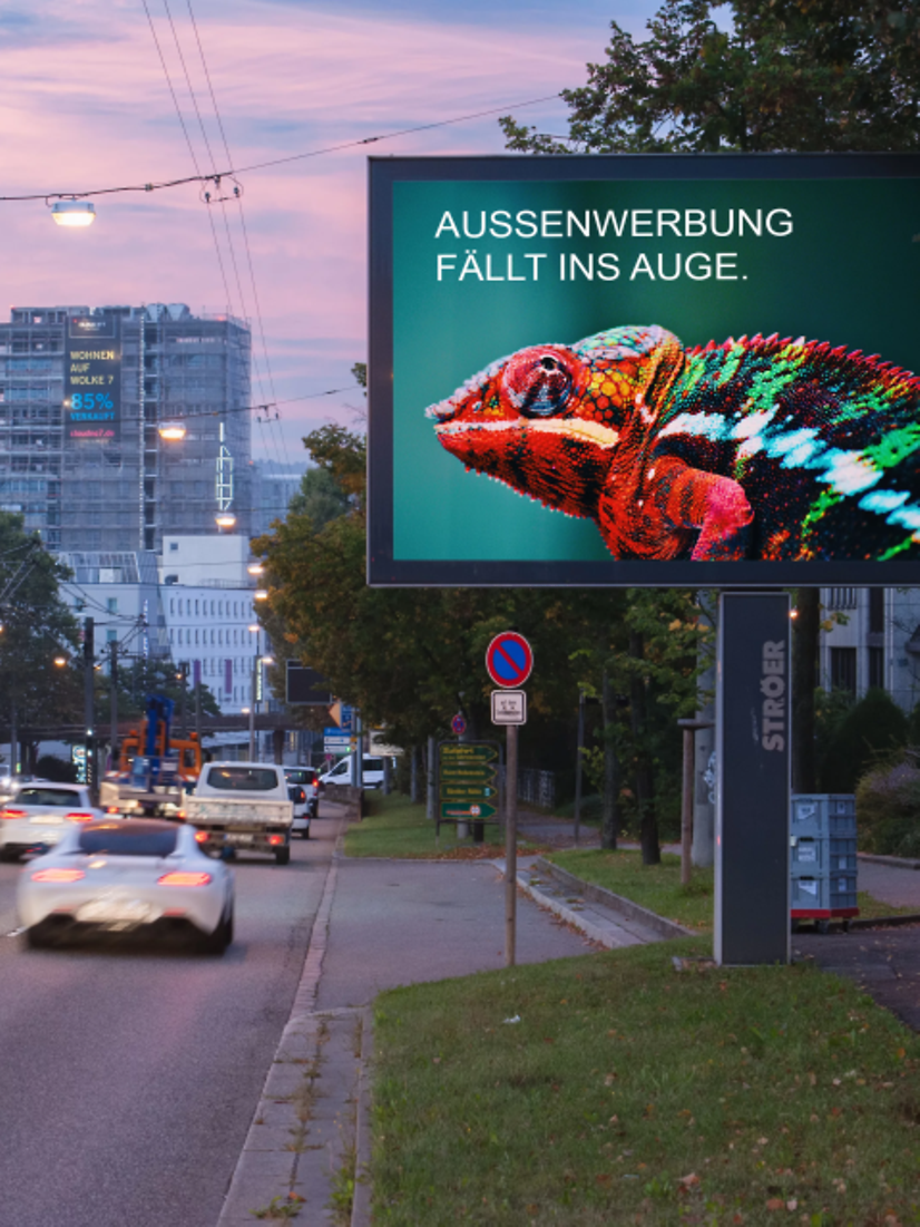 Image shows an illuminated Citylight on a busy main road in Stuttgart during the early evening hours.