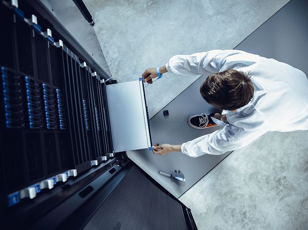 An IT engineer removes a panel from a network server.