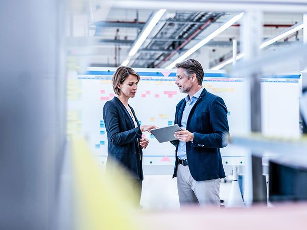 Businesswoman and businessman conversing in a factory hall
