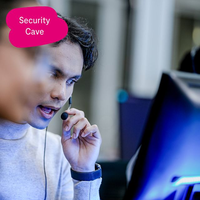 Person mit Headset arbeitet konzentriert an einem Desktop-Monitor in einer Büroumgebung.