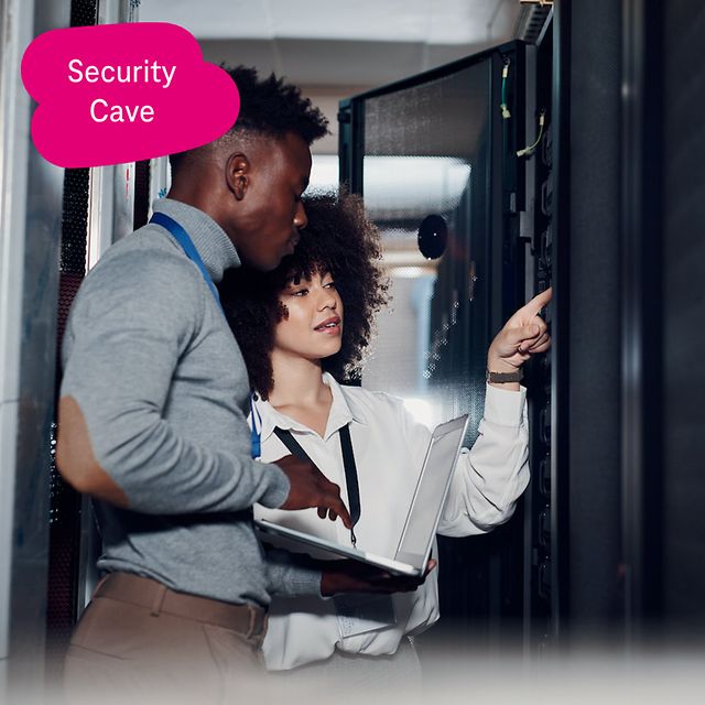 Two IT specialists are standing in front of an open server cabinet in the data centre.