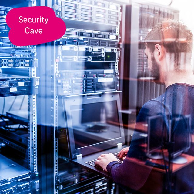 T-Administrator works on a pull-out laptop in front of a server cabinet in a data centre.
