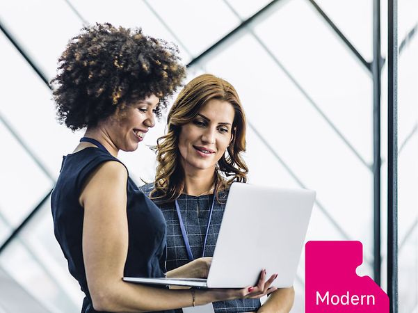 Zwei Business-Frauen blicken gemeinsam auf einen geöffneten Laptop, daneben ein Icon mit der Aufschrift „Modern Work“.