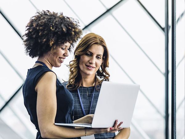 Two businesswomen look together at an open laptop, next to which is an icon labelled 'Modern Work'.
